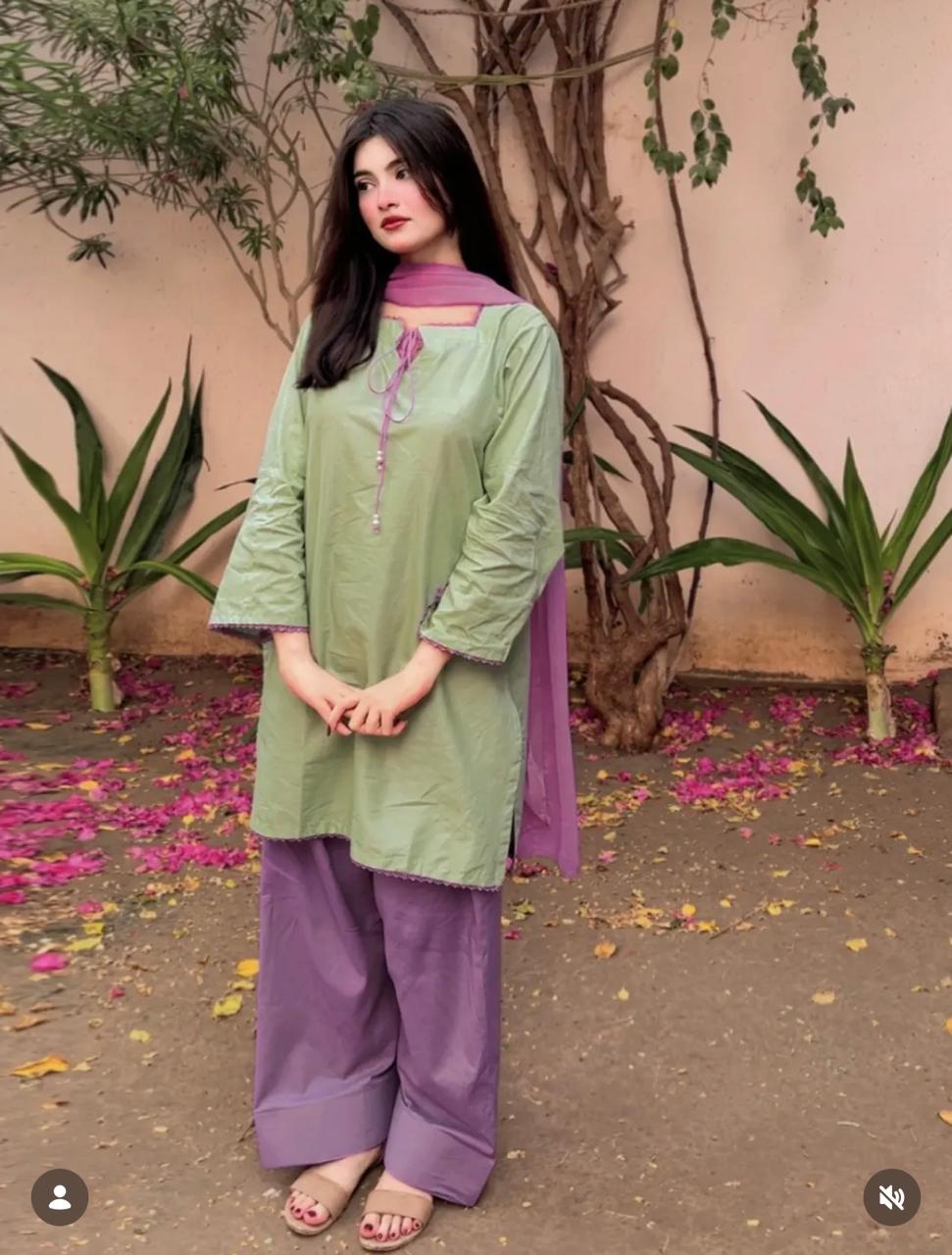 Front view of model wearing the Zarysh Premium Stitched Lawn 3-Piece suit featuring a pistachio green shirt and lavender trousers in an outdoor garden setting.