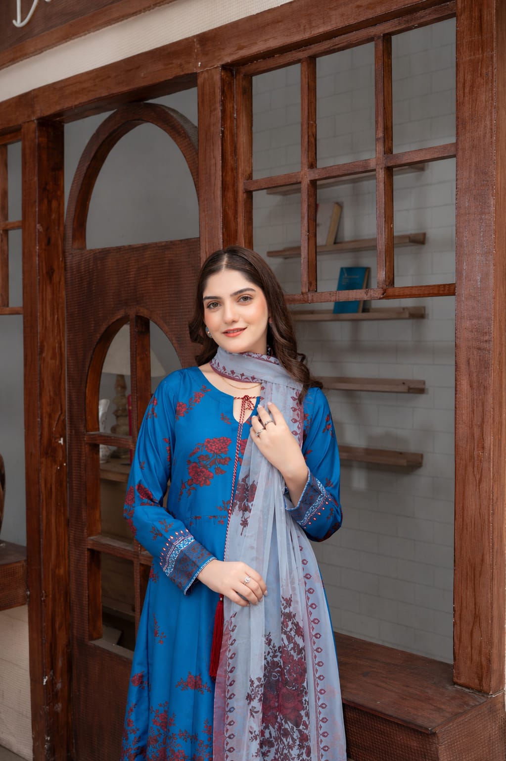 Woman wearing a blue embroidered dress with a matching dupatta in a wooden interior setting